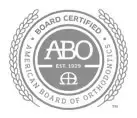 Seal of the American Board of Orthodontics, featuring "ABO" and "EST. 1929" in the center with the words "Board Certified" and "American Board of Orthodontics" encircling it, bordered by laurel branches.