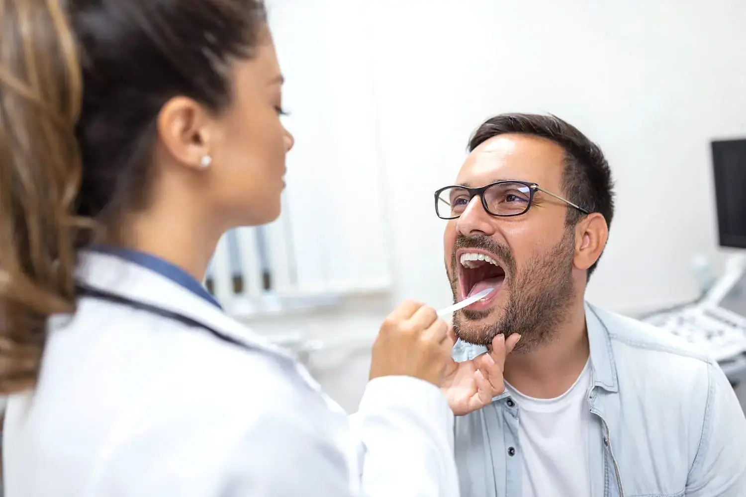 At Natalie Yang Orthodontics Orthodontics in Vacaville, CA, a healthcare professional uses a tongue depressor to examine a man's throat for signs of an underbite. At Natalie Yang Orthodontics Orthodontics in Vacaville, CA, a healthcare professional uses a tongue depressor to examine a man's throat for signs of an underbite.