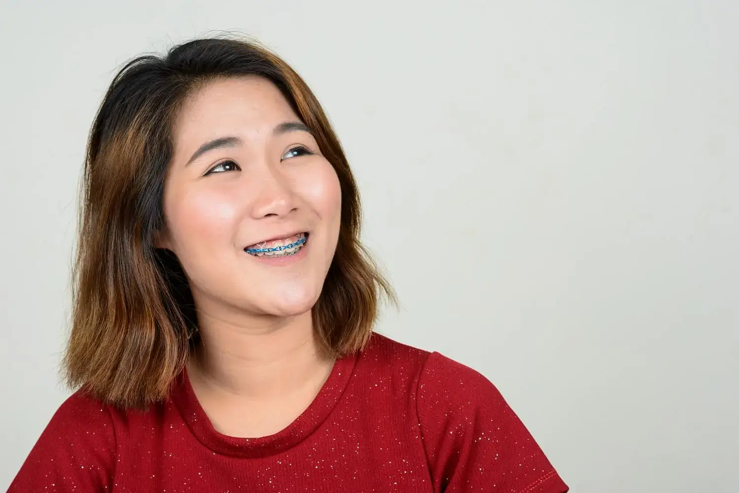 Smiling young woman with brown hair, red shirt, and braces at Natalie Yang Orthodontics Orthodontics in Vacaville, CA. Smiling young woman with brown hair, red shirt, and braces at Natalie Yang Orthodontics Orthodontics in Vacaville, CA.