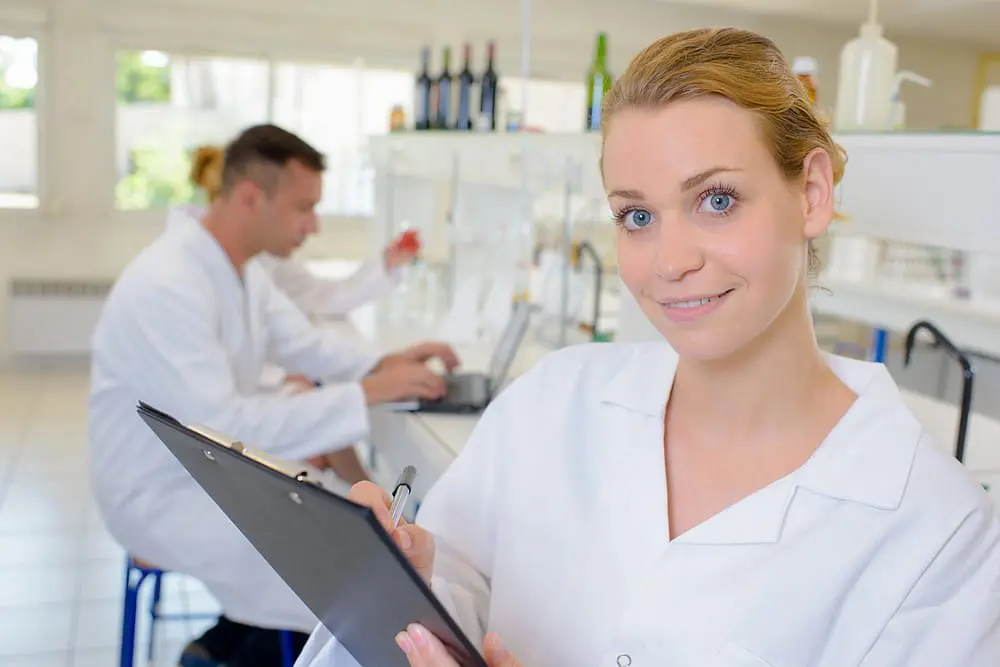 A woman in a lab coat smiles with a clipboard representing all PPO insurance plans accepted at Natalie Yang Orthodontics in Vacaville, CA.